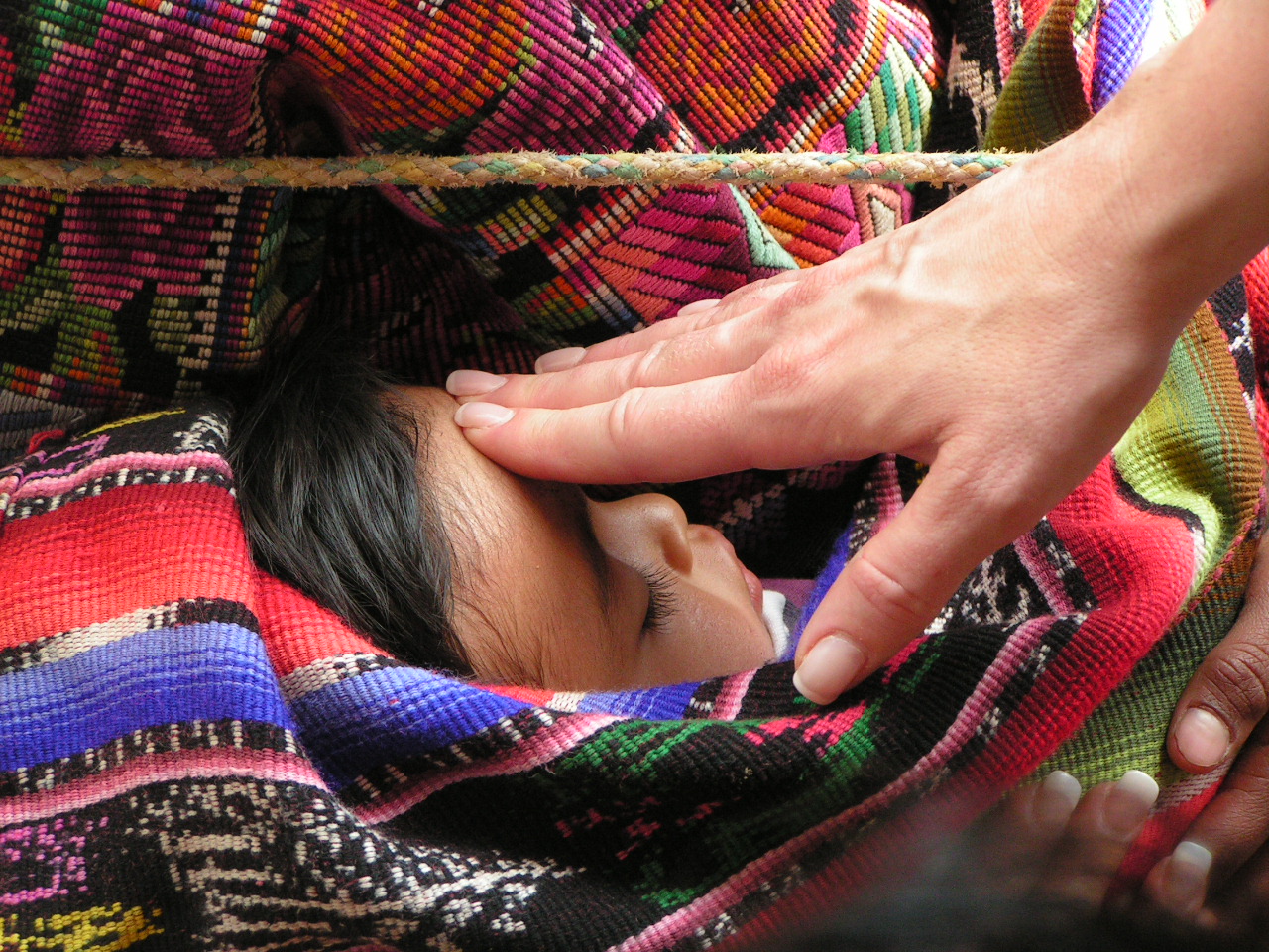 A hand touching little girl's forehead 